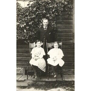 Vtg 1900's RPPC Father Posing With Two Daughters Sitting In Chair Outside